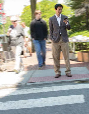 Andrew Ho checks his phone on the sidewalk.
