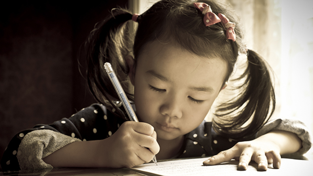 a young girl writes on a piece of paper