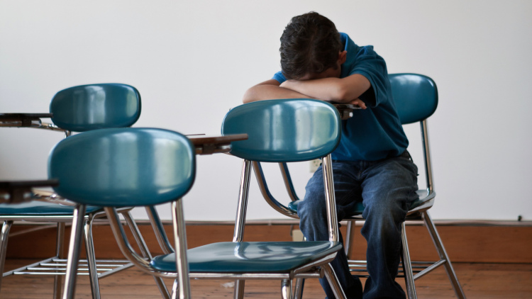 Boy sitting in classroom with head down