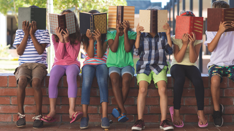 Diverse group of kids hiding behind books