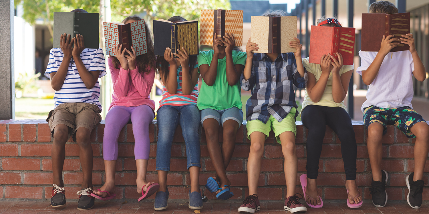 Diverse group of kids hiding behind books