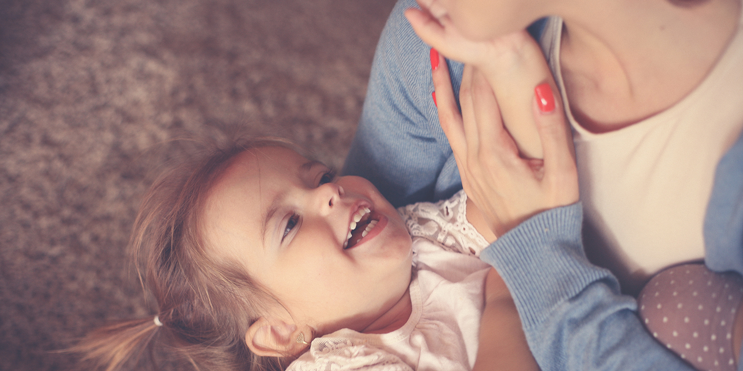 Young girl smiles up at her mother
