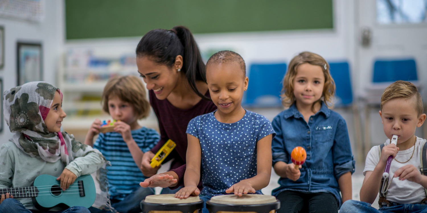a diverse group of young students playing musical instruments with a teacher