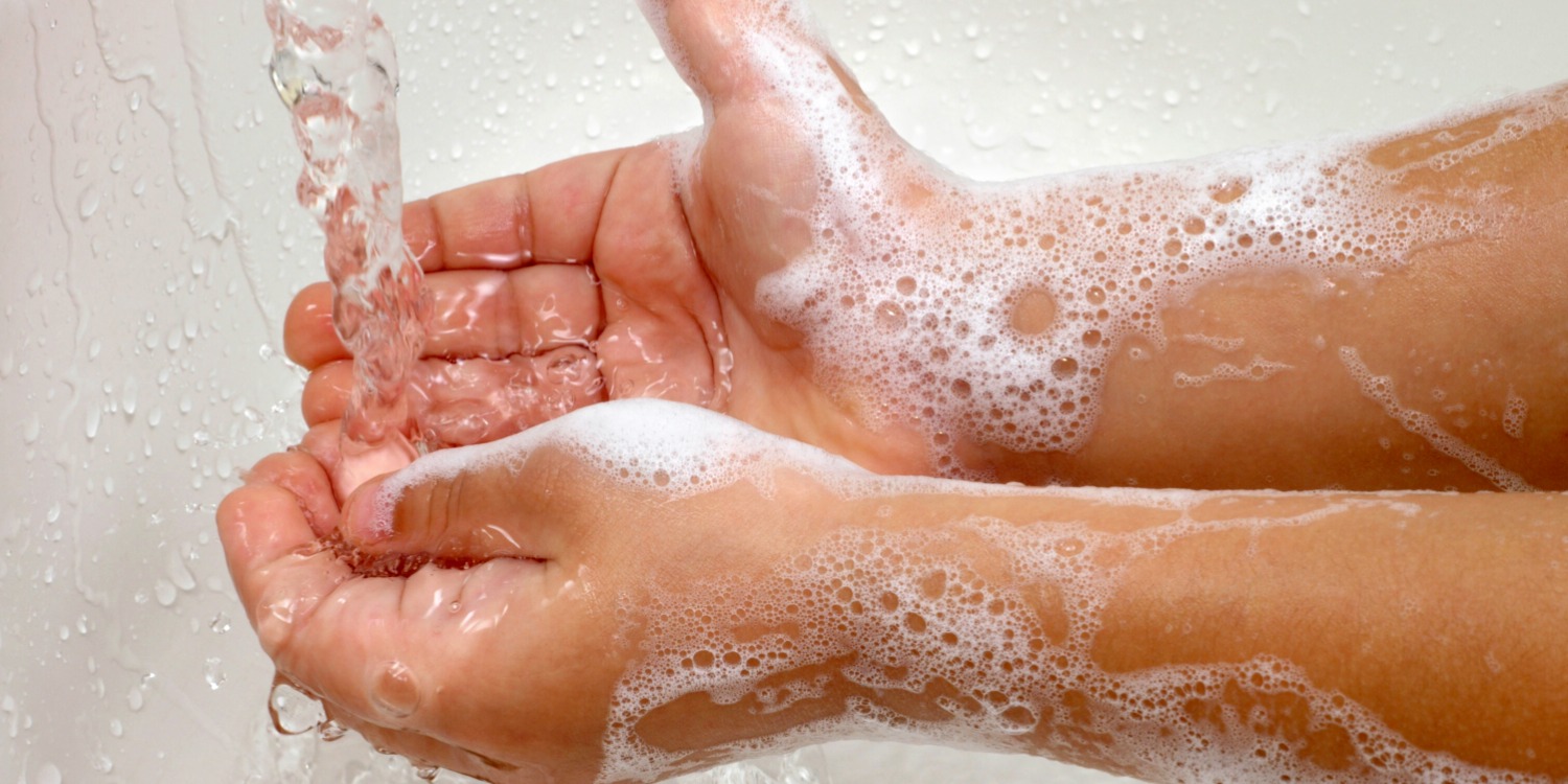 a child's soapy hands under running water
