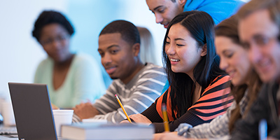 multicultural group of students working around a laptop