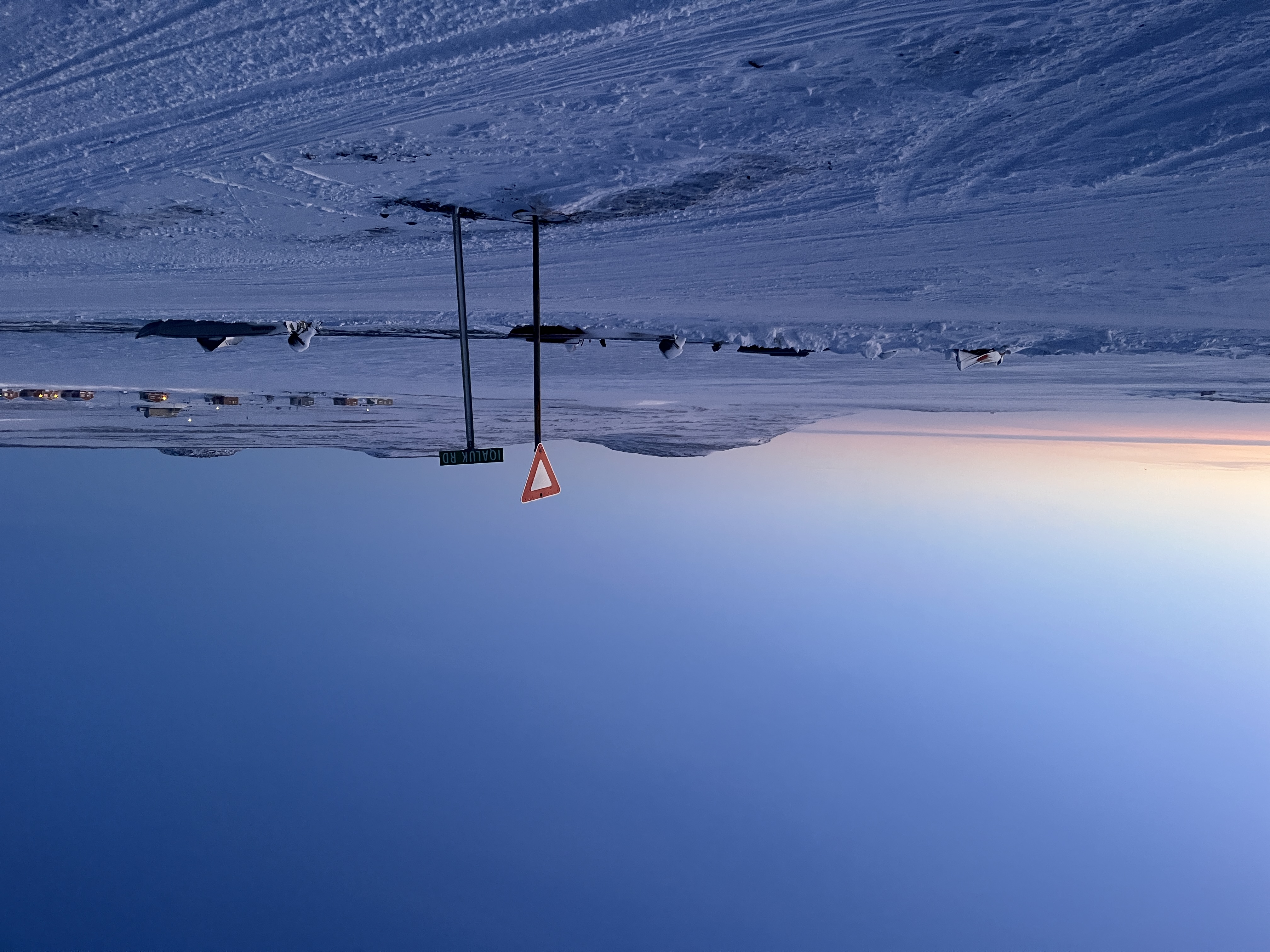 Two street signs stand on a snow-covered bath in the arctic