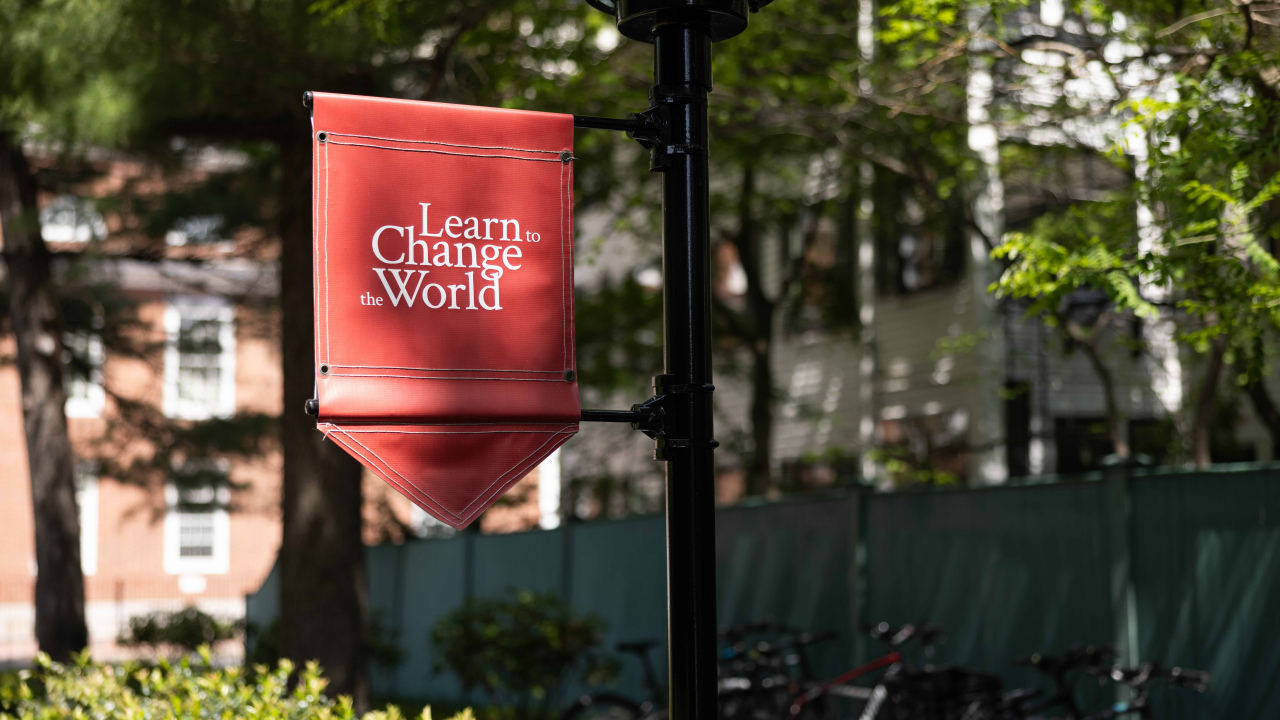 Crimson flag that reads "learn to change the world" on campus at HGSE