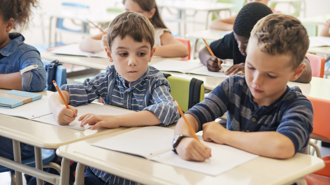 A young boy looks at his classmate's work