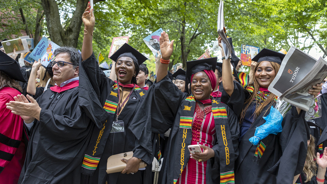 graduates cheering with books