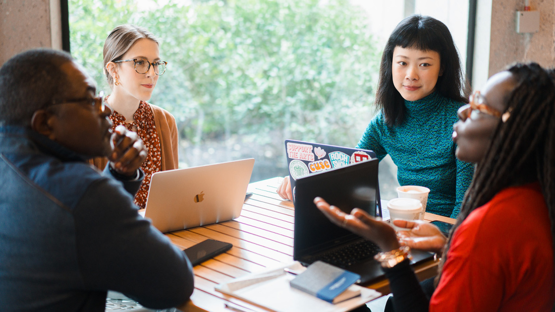 Students and faculty member sitting around a table at window