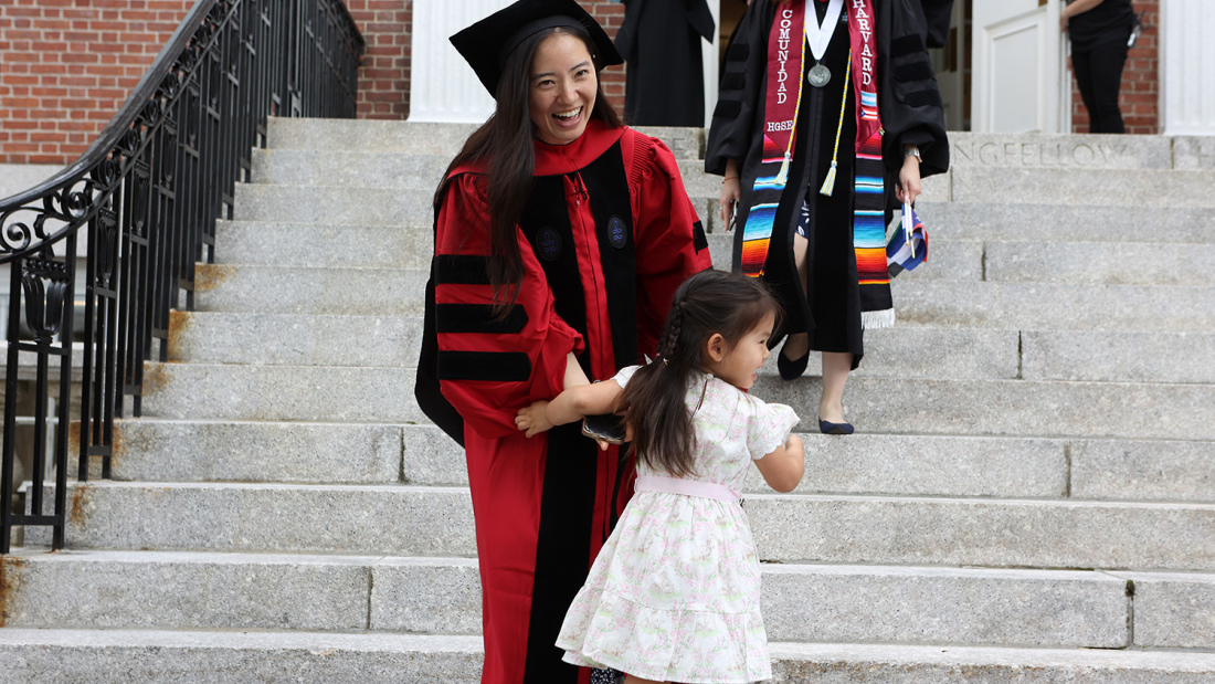 Graduate with child near stairs