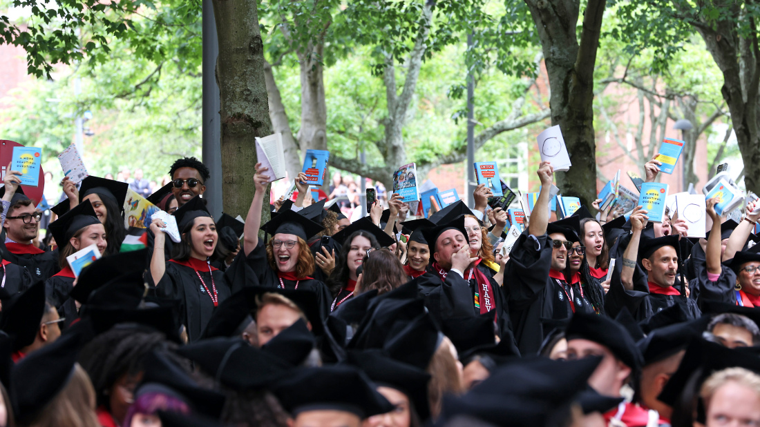 Grads holding books in Harvard Yard
