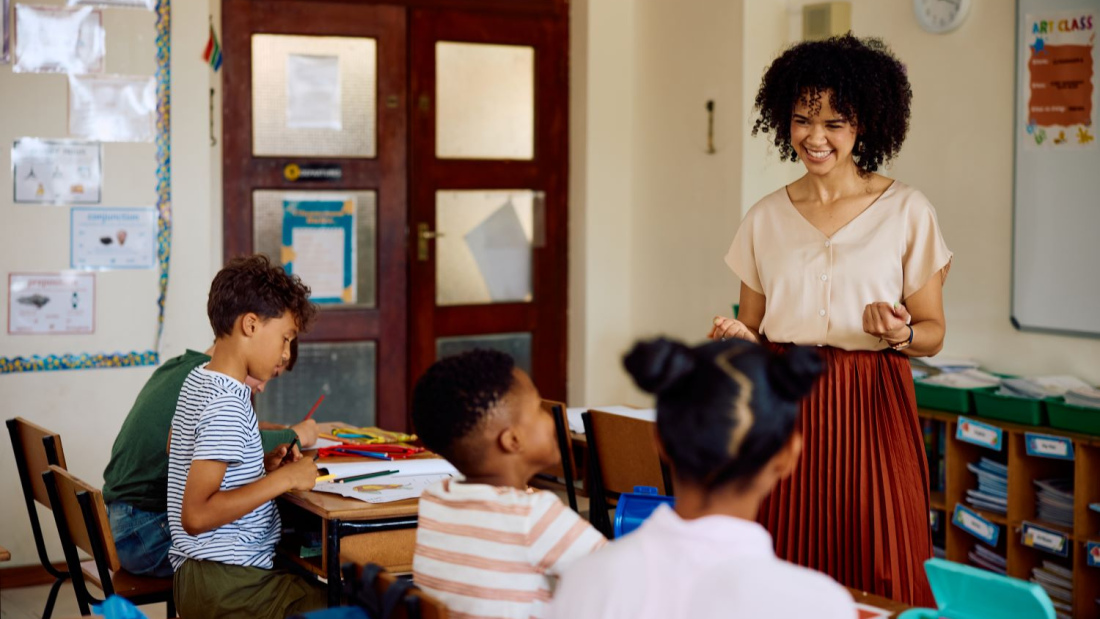 Elementary school teacher smiles while having a discussion with her class