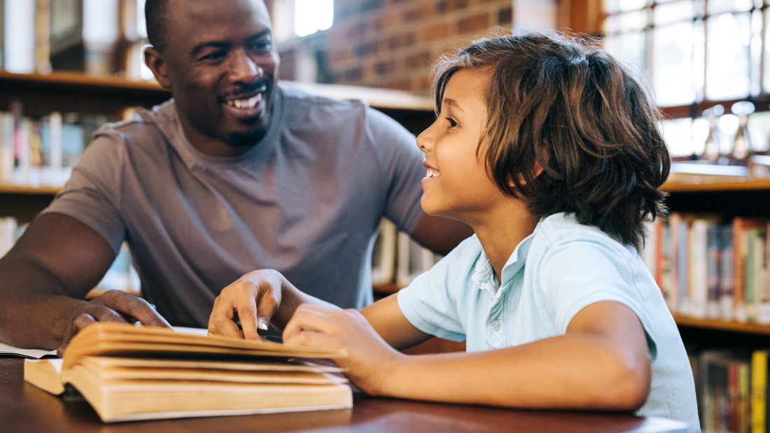 Male tutor with elementary student in library