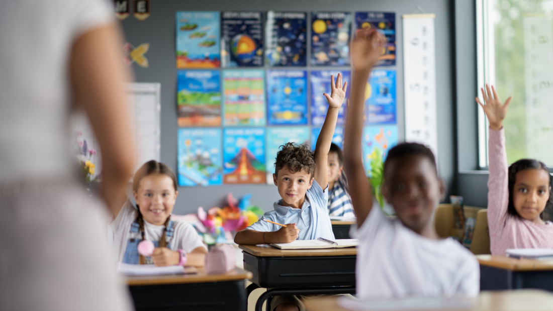 students raise their hands in middle school science class