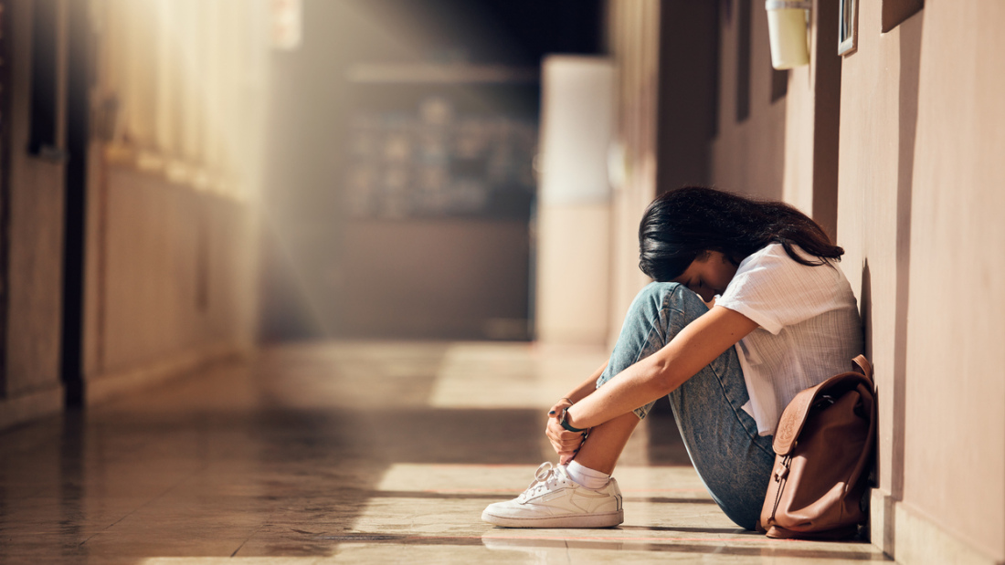 college student sitting alone in an empty hallway