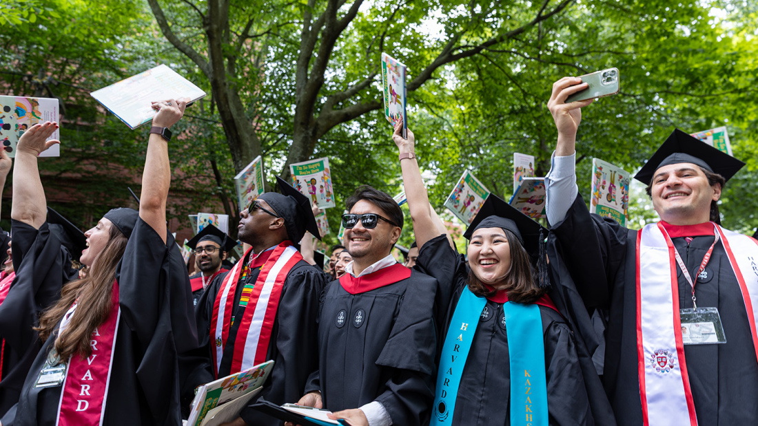 Grads holding books in Harvard Yard
