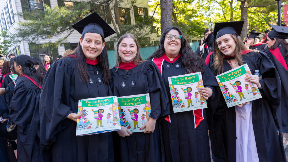 Four master's students holding Mychal Threets' book, "I'm So Happy You're Here"
