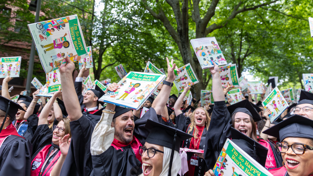 Students at the Harvard Commencement with their copy of Mychal Threets' book titled "I'm So Happy You're Here"