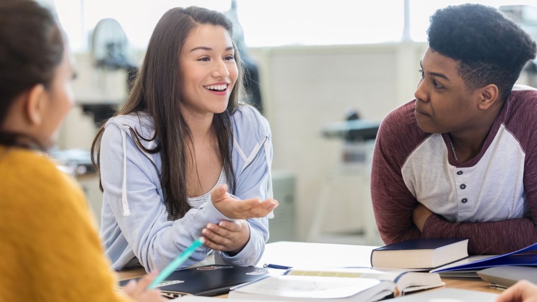 Three high school students have a conversation in class