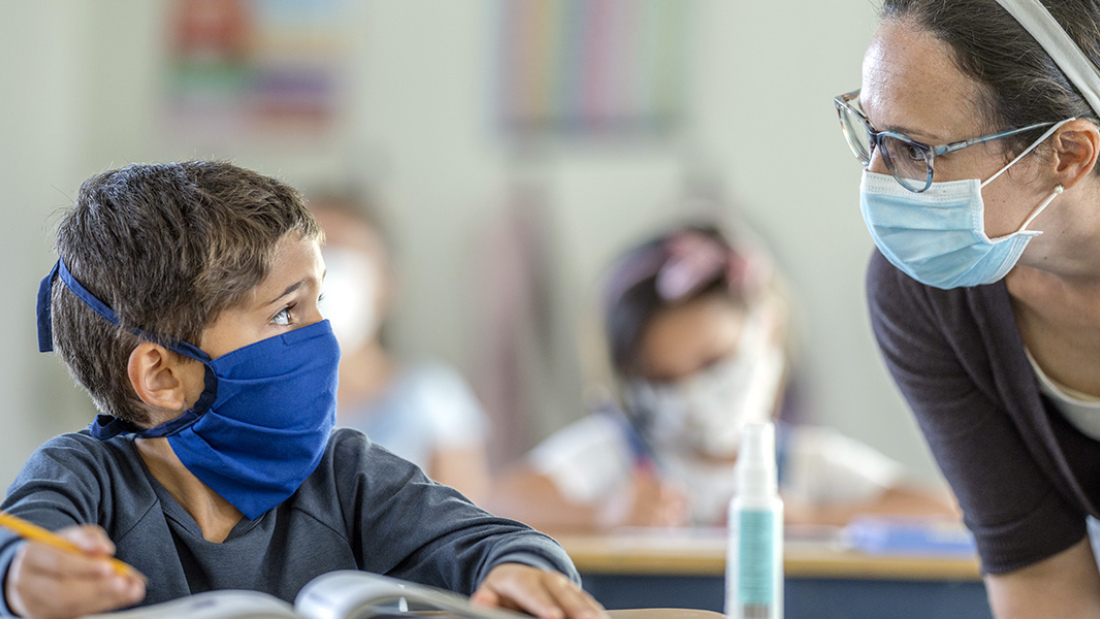 Child and teacher wearing masks in school