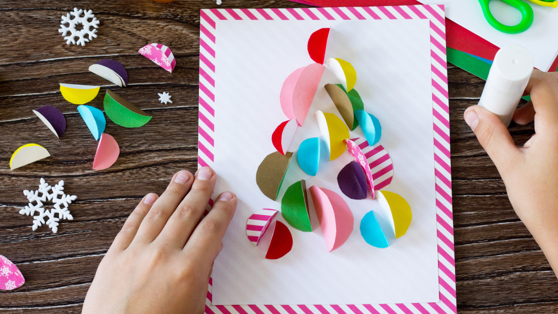 Child's hands making a card out of construction paper