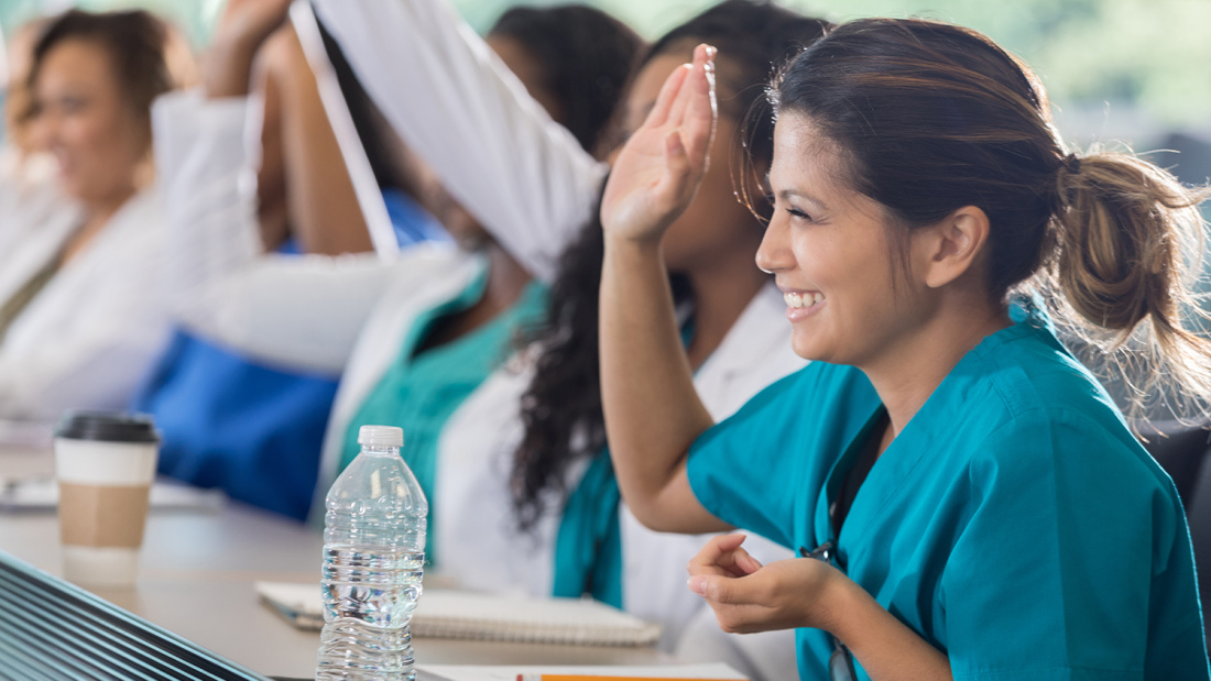 Row of students in medical training class, with smiling woman in front