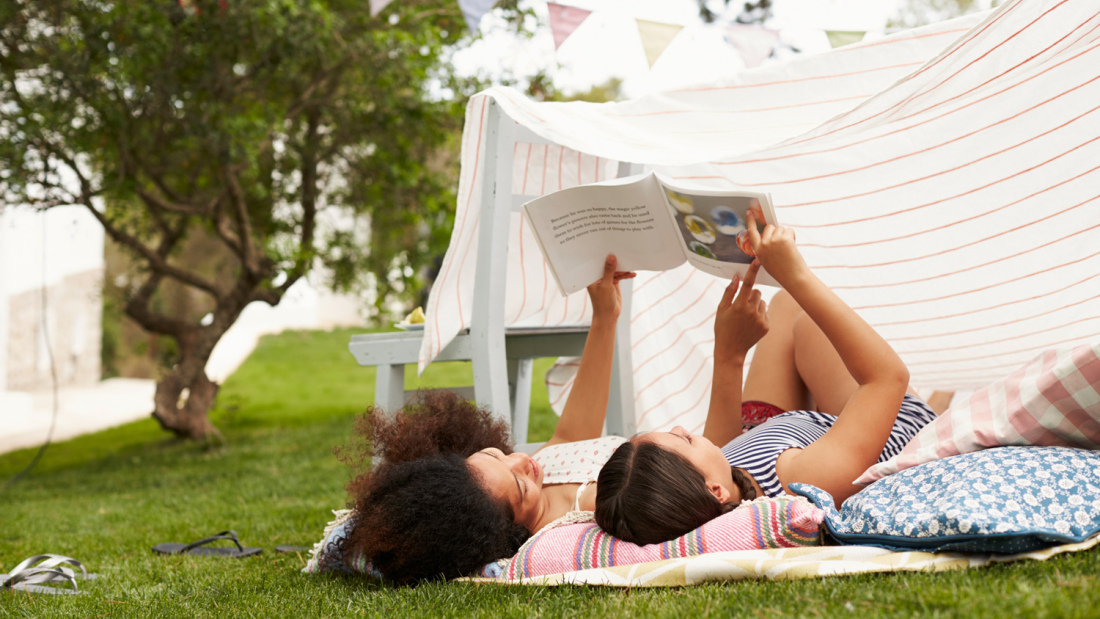A mother and her daughter reading a book outside