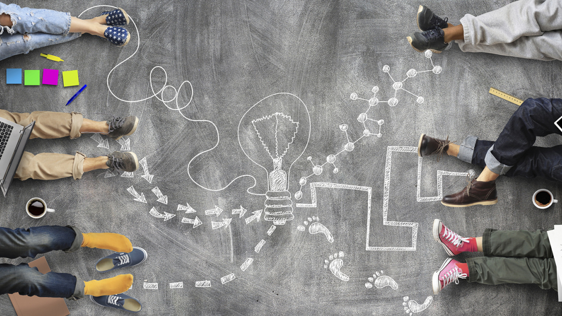 Teens with laptops and a chalk drawing of lightbulb