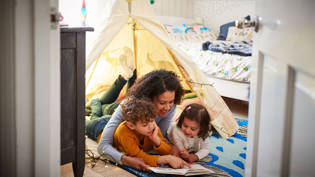 Mother reading to son and daughter in play tent