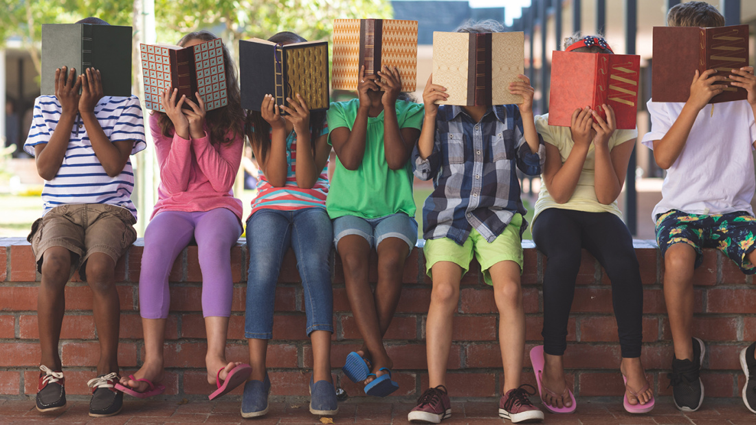 Diverse group of kids hiding behind books