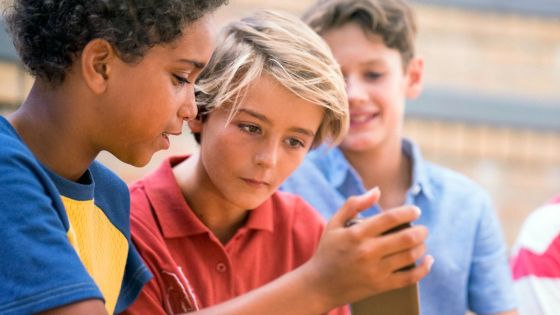 Group of tween boys looking at a cell phone