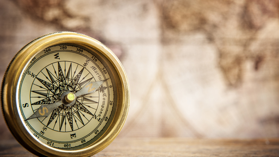 antique bronze compass, with blurry antique map in the background