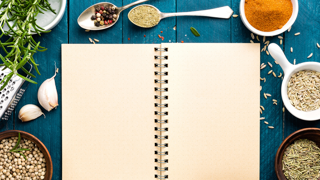 A blank page in an open notebook, surrounded by cooking ingredients