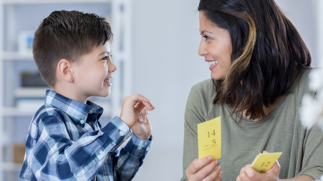 young boy and mother smiling at each other, with math flashcards