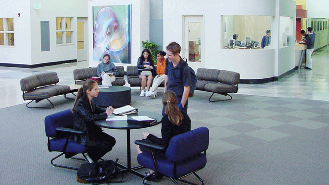 photo of a new school building, with students in open lobby area 