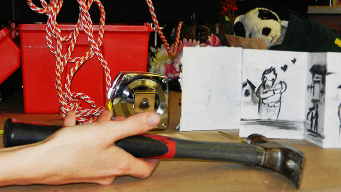 photo of hand with hammer and crafts in background