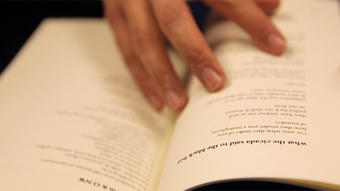 Hands shown opening a book of poems