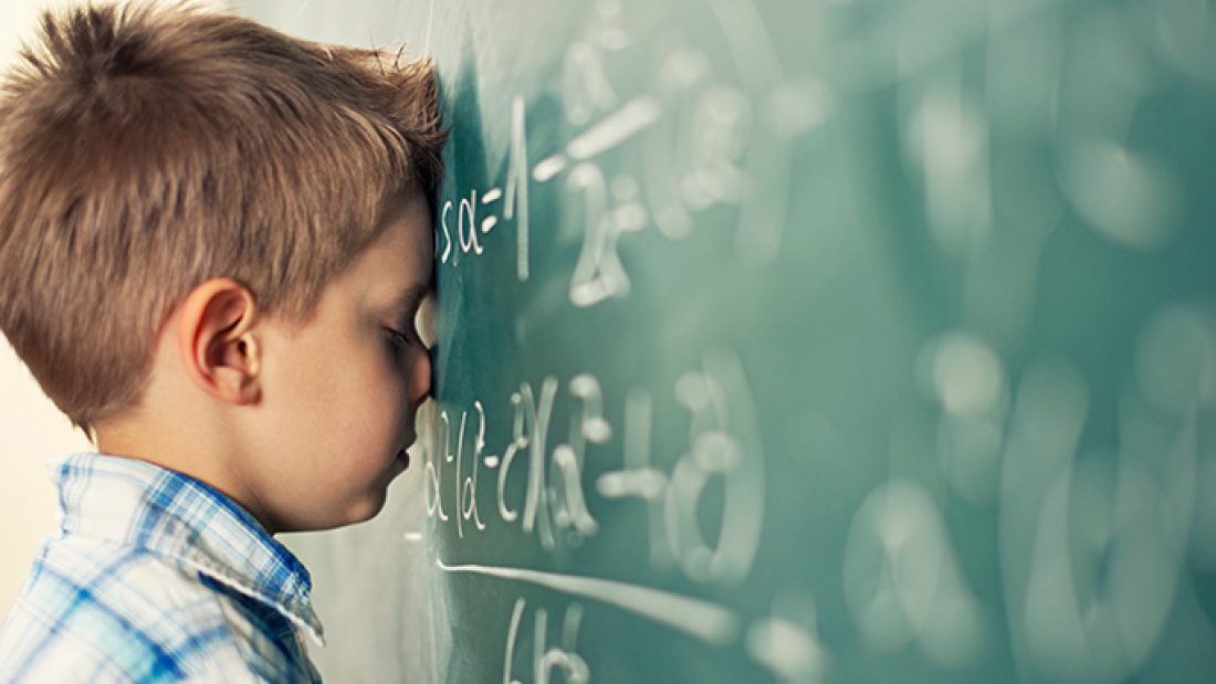 boy resting head on number-covered blackboard