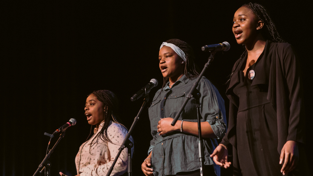 Photo of three African American female students standing at microphones