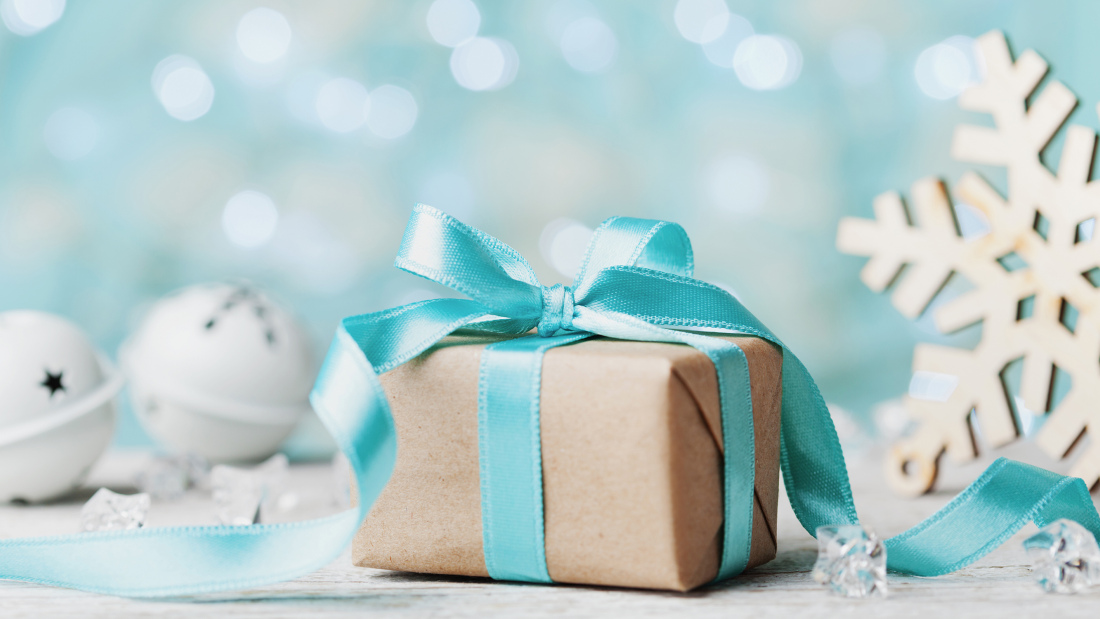 Picture of a brown wrapped gift and snowflake against a blue background