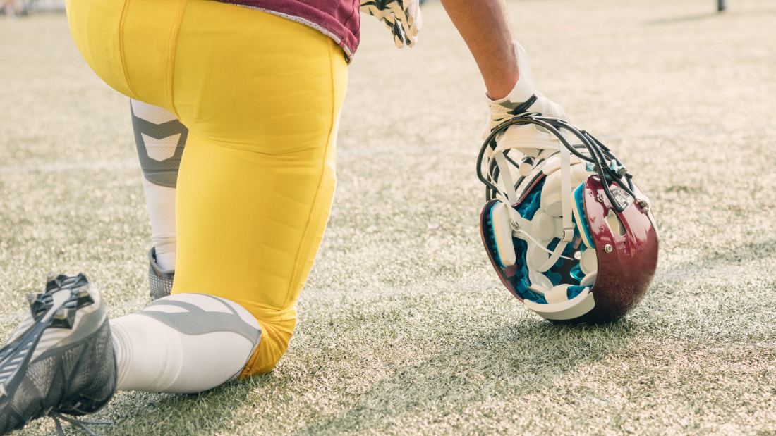 A photo of a football player kneeling next to his helmet