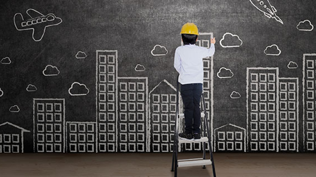 Boy drawing a city on a blackboard