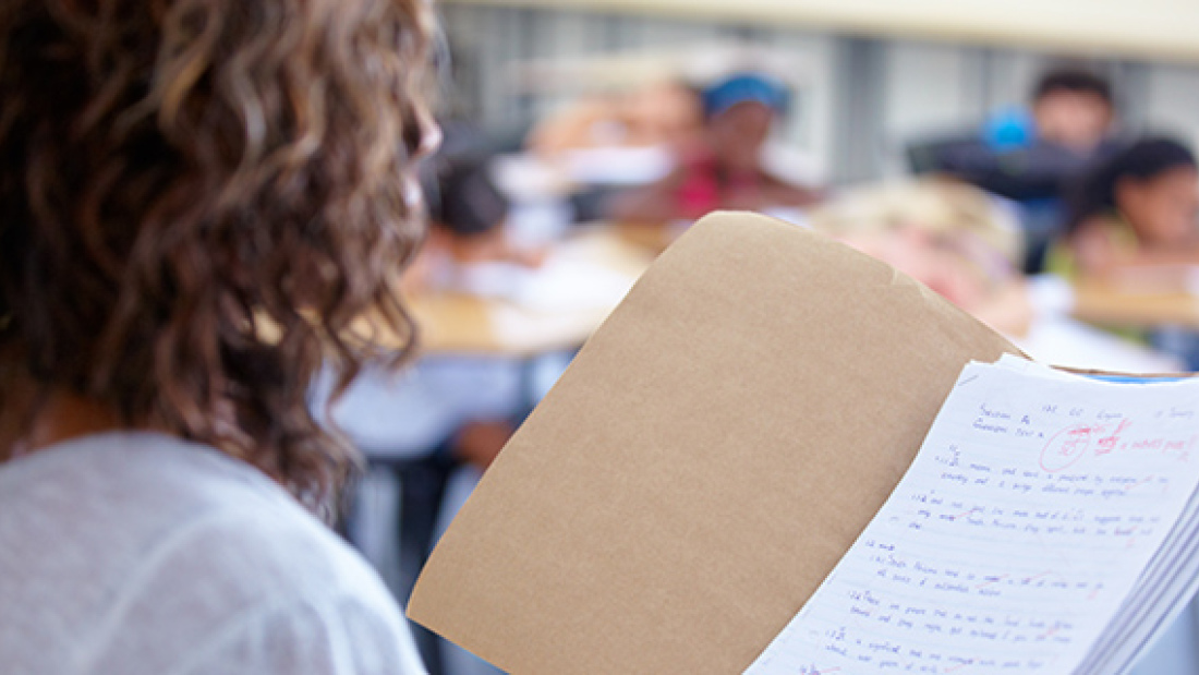 conceptual photo of teacher holding folder of graded papers