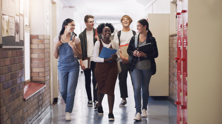 A group of teenage students walking down the hall at high school.