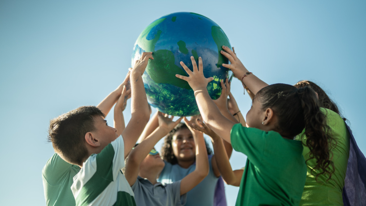 Children holding a globe outdoors.