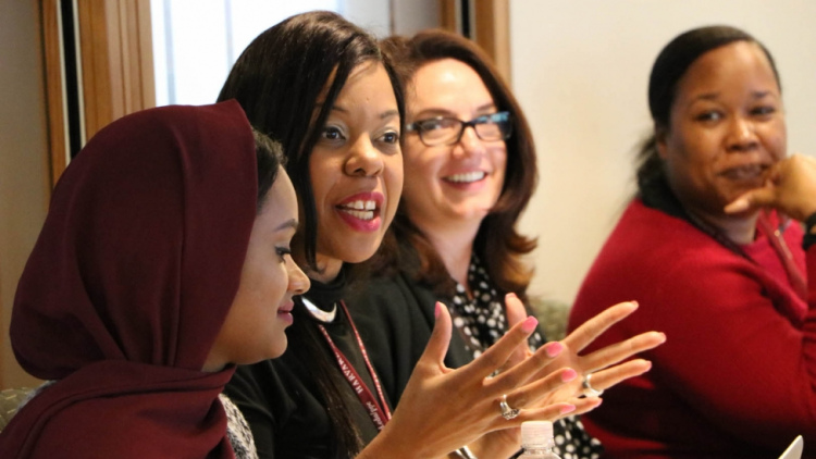 A woman speaks during the program, and the women beside her smile and listen.