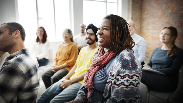 A black women sits in a crowd smiling.