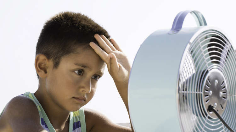 Overheated boy in front of fan