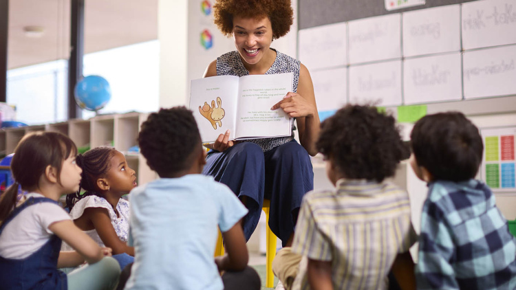Teacher reading a book in front of classroom